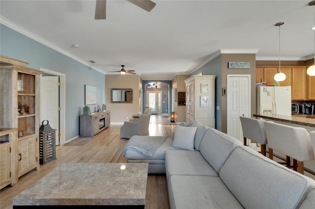 living room featuring ceiling fan, ornamental molding, and light wood-type flooring