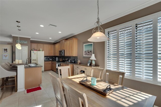 dining space featuring light tile patterned floors, ornamental molding, a healthy amount of sunlight, and sink