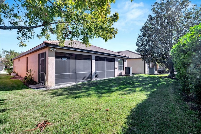 back of property featuring a sunroom, a lawn, and central AC