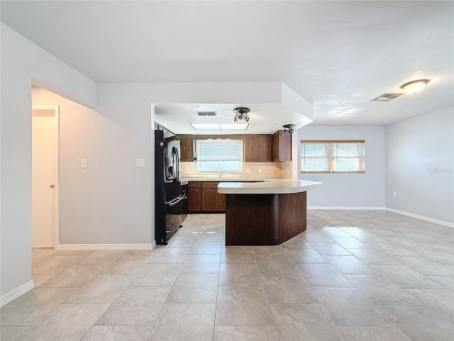 kitchen featuring light tile patterned flooring and black refrigerator with ice dispenser