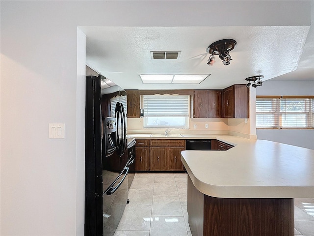 kitchen with black appliances, sink, kitchen peninsula, and a textured ceiling