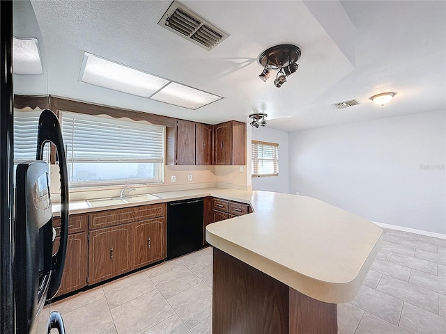 kitchen featuring sink, light tile patterned floors, black dishwasher, fridge, and kitchen peninsula