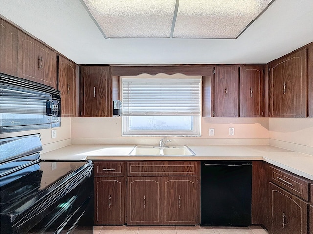 kitchen featuring black appliances, dark brown cabinetry, light tile patterned floors, and sink