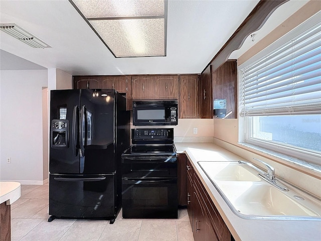 kitchen with black appliances, dark brown cabinets, light tile patterned flooring, and sink