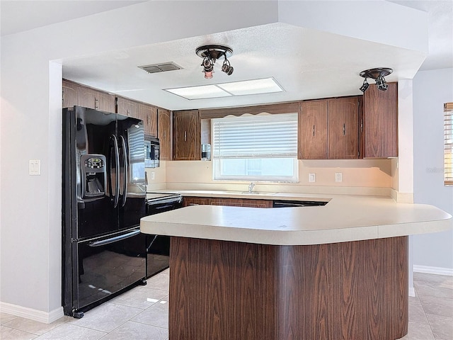 kitchen with black appliances, light tile patterned flooring, kitchen peninsula, and sink