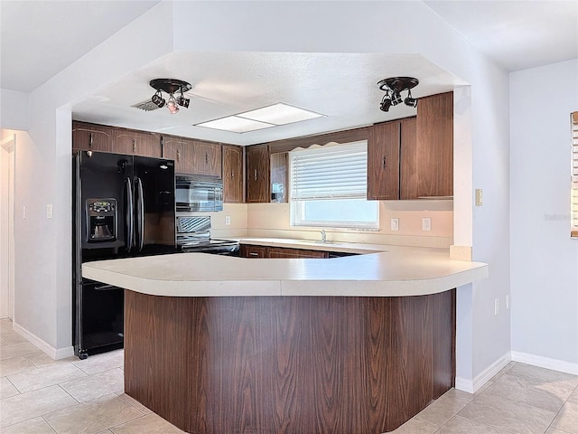 kitchen featuring kitchen peninsula, light tile patterned floors, sink, and black appliances