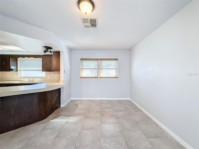 kitchen featuring light tile patterned flooring and dark brown cabinetry