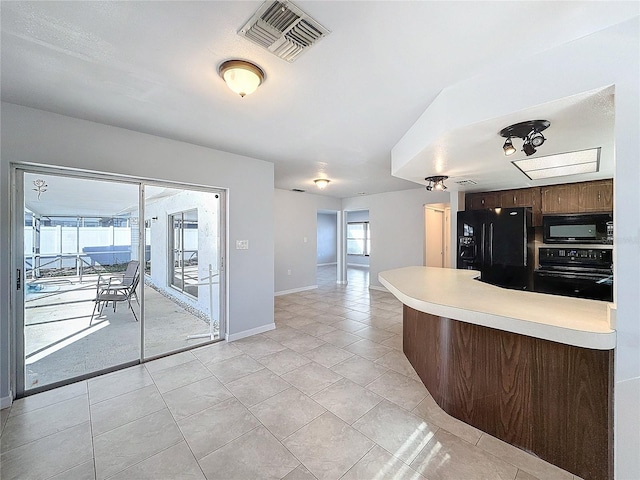 kitchen with black appliances, a healthy amount of sunlight, and light tile patterned floors