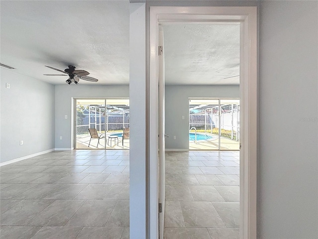 entryway with ceiling fan, light tile patterned floors, and a textured ceiling