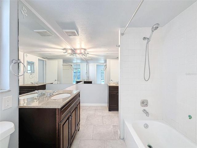 full bathroom with tile patterned flooring, a textured ceiling, toilet, vanity, and tiled shower / bath