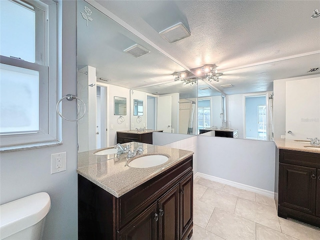 bathroom featuring tile patterned flooring, vanity, a textured ceiling, and toilet