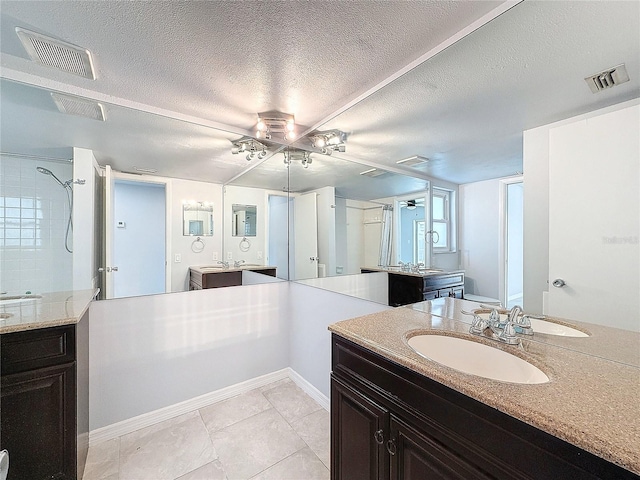 bathroom featuring tile patterned floors, a tile shower, vanity, a textured ceiling, and ceiling fan