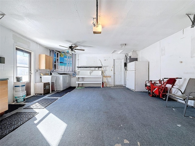 garage featuring ceiling fan, white fridge, washing machine and dryer, and a garage door opener