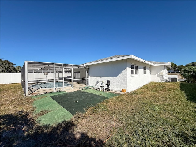 rear view of house with a fenced in pool, a lanai, a yard, central AC, and a patio area