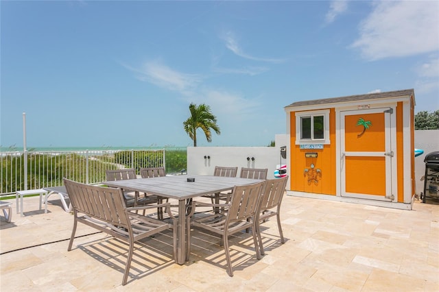 view of patio / terrace featuring a water view and a storage unit