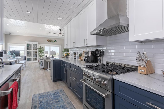 kitchen featuring white cabinets, backsplash, stainless steel stove, and wall chimney exhaust hood