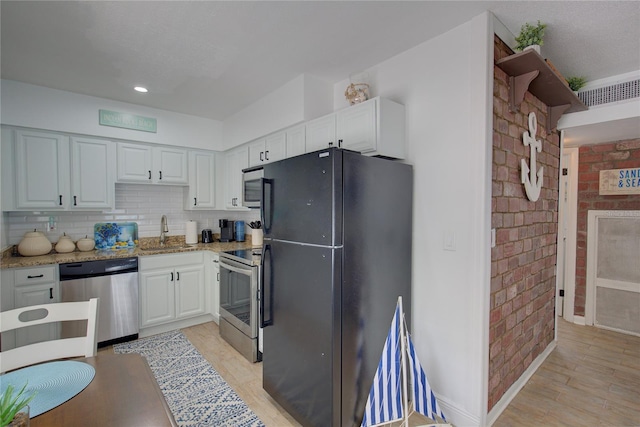 kitchen featuring light stone countertops, appliances with stainless steel finishes, tasteful backsplash, sink, and white cabinets