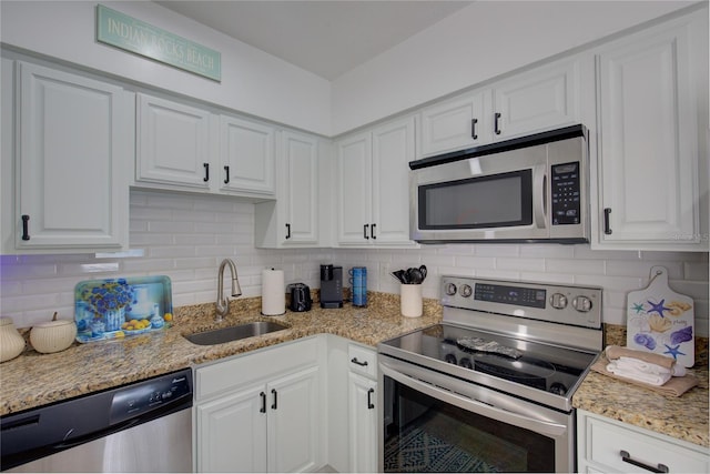 kitchen featuring white cabinets, sink, decorative backsplash, light stone countertops, and stainless steel appliances