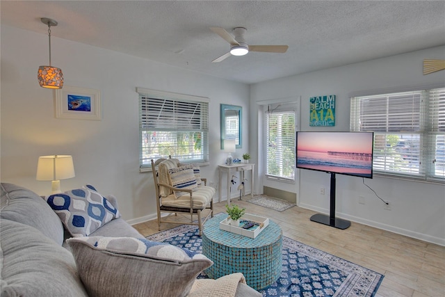 living room with ceiling fan, light hardwood / wood-style flooring, and a textured ceiling