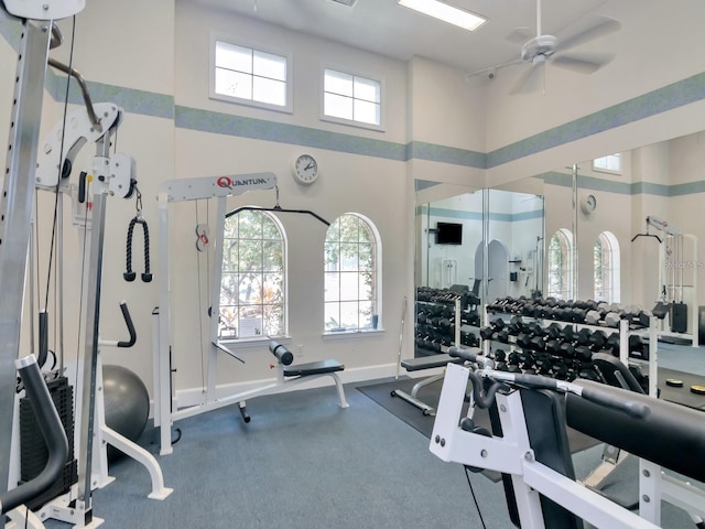 exercise room with a towering ceiling and ceiling fan