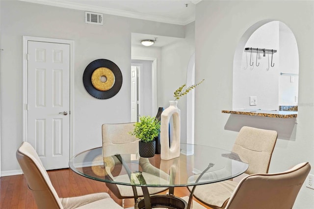 dining area with wood-type flooring and ornamental molding