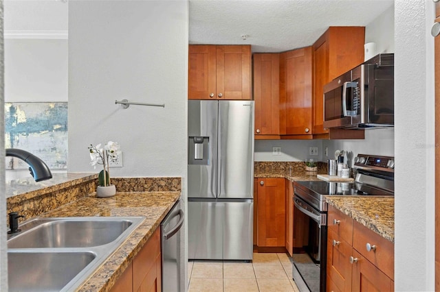 kitchen featuring sink, light tile patterned floors, stainless steel appliances, and stone counters