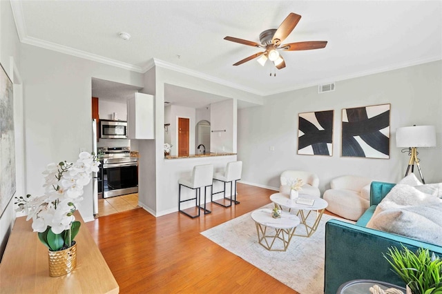 living room with ceiling fan, sink, crown molding, and light hardwood / wood-style flooring