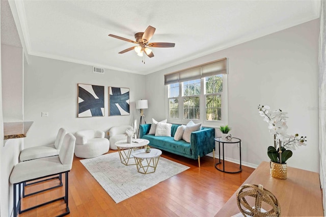 living room featuring a textured ceiling, hardwood / wood-style flooring, ceiling fan, and ornamental molding