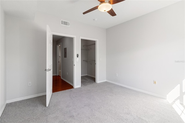 unfurnished bedroom featuring electric panel, carpet flooring, ceiling fan, a spacious closet, and a closet