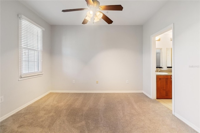 unfurnished room featuring ceiling fan, light colored carpet, and sink