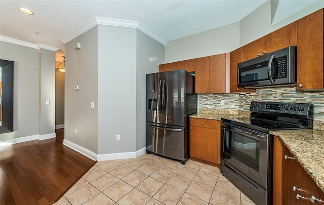 kitchen featuring backsplash, crown molding, light hardwood / wood-style flooring, light stone counters, and stainless steel appliances