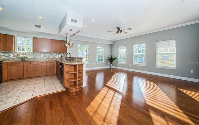 kitchen with decorative backsplash, pendant lighting, light wood-type flooring, and sink