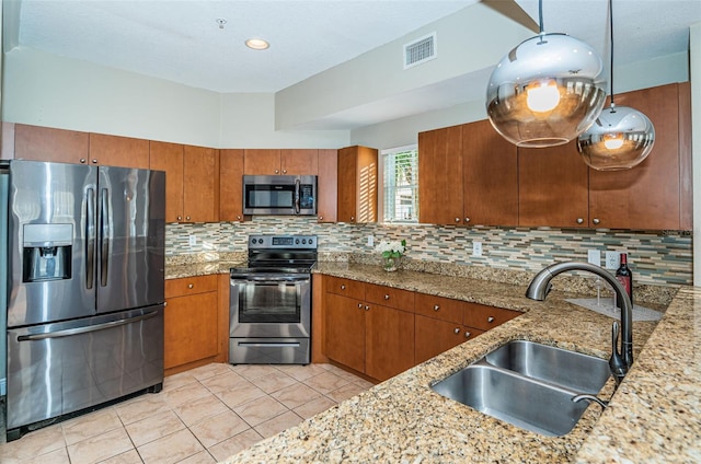 kitchen featuring light stone countertops, decorative backsplash, stainless steel appliances, sink, and light tile patterned floors