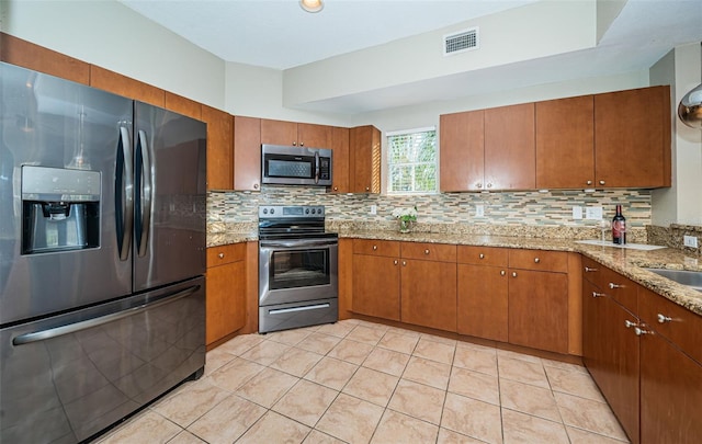 kitchen featuring sink, stainless steel appliances, light stone counters, decorative backsplash, and light tile patterned floors