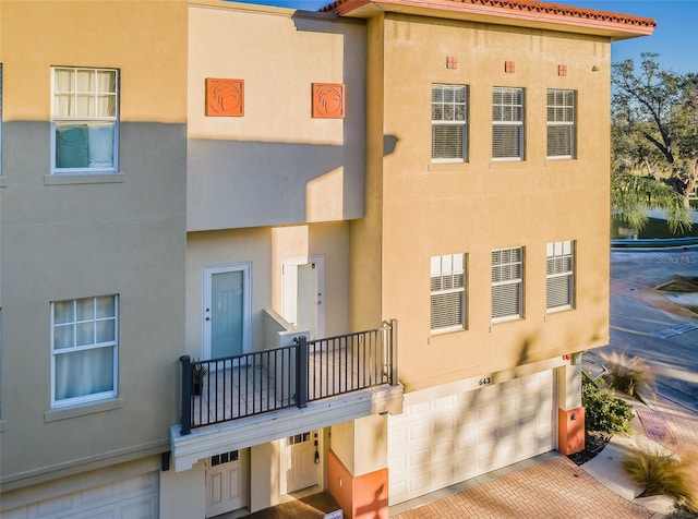 rear view of property featuring a balcony and a garage