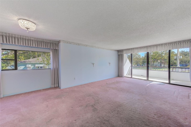 empty room featuring carpet, a textured ceiling, and an inviting chandelier