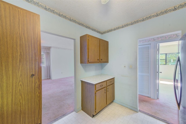 kitchen with stainless steel fridge, light colored carpet, and a textured ceiling