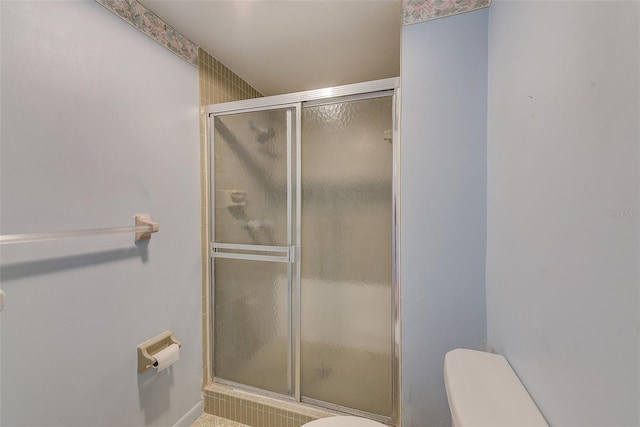 bathroom featuring toilet and a shower with door