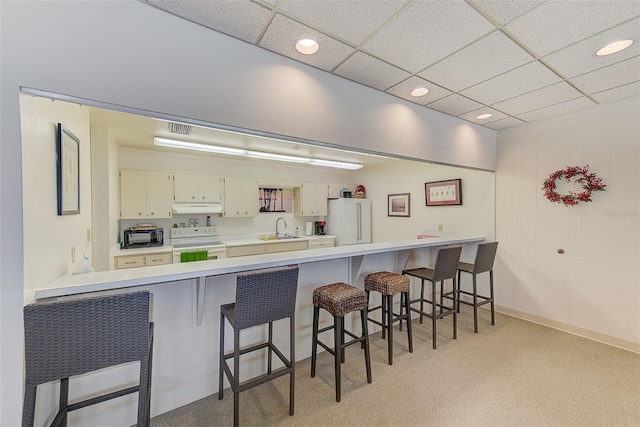 kitchen featuring white cabinets, kitchen peninsula, white appliances, and sink