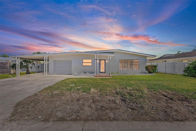 view of front of property with a carport, a garage, and a lawn