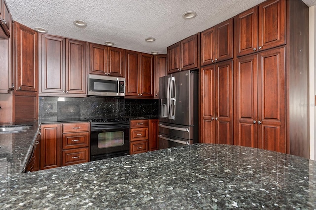 kitchen featuring decorative backsplash, stainless steel appliances, dark stone countertops, and sink