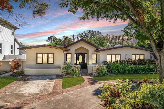 view of front of property with stucco siding and a lawn