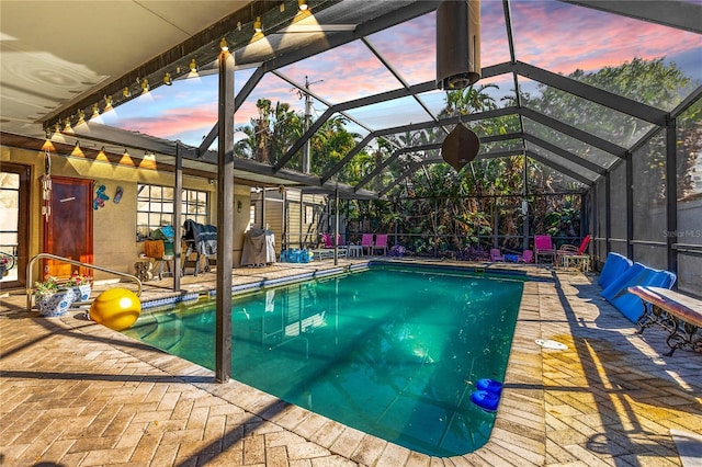 pool at dusk with a lanai and a patio area