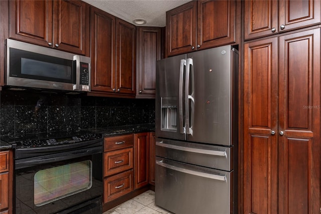 kitchen with dark stone countertops, light tile patterned floors, stainless steel appliances, and a textured ceiling