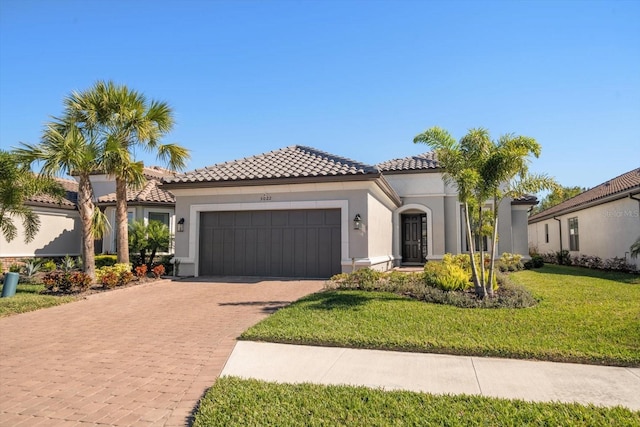 mediterranean / spanish home featuring a garage and a front yard