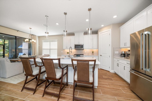 kitchen with plenty of natural light, white cabinets, stainless steel appliances, and light hardwood / wood-style flooring