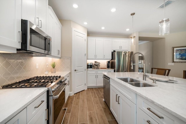 kitchen featuring white cabinets, decorative light fixtures, light hardwood / wood-style floors, and appliances with stainless steel finishes