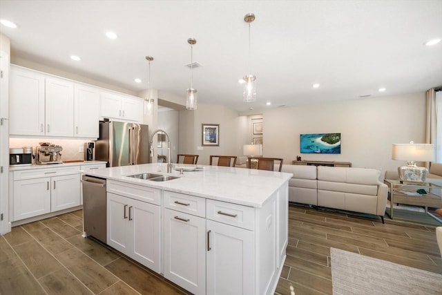 kitchen featuring white cabinets, an island with sink, hanging light fixtures, and sink