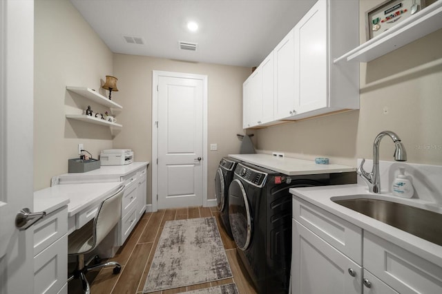 laundry area featuring cabinets, dark hardwood / wood-style floors, washing machine and dryer, and sink