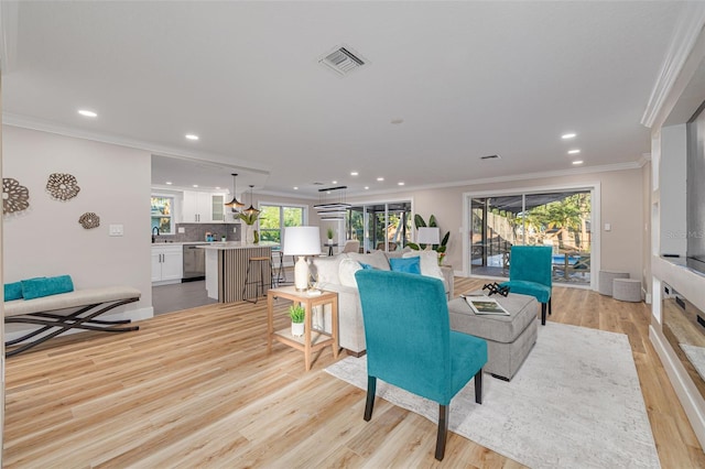 living room featuring ornamental molding, recessed lighting, visible vents, and light wood-type flooring